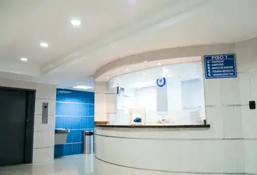 Reception area with white curved desk, blue accent wall, and elevator in a corporate office environment.