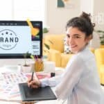 Young woman working on digital branding project with graphic design tools and colour palettes.