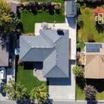 Aerial view of a contemporary family home featuring a spacious backyard, driveway, and surrounding greenery in Beverly Hills, NSW.
