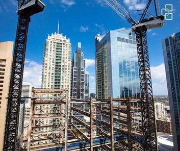 Construction cranes and high-rise buildings under development in an urban setting.