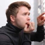 Starting PAYG Instalments for Your Business Young man in a black turtleneck carefully examining financial documents or tax forms, possibly in an office setting, with a focused expression.