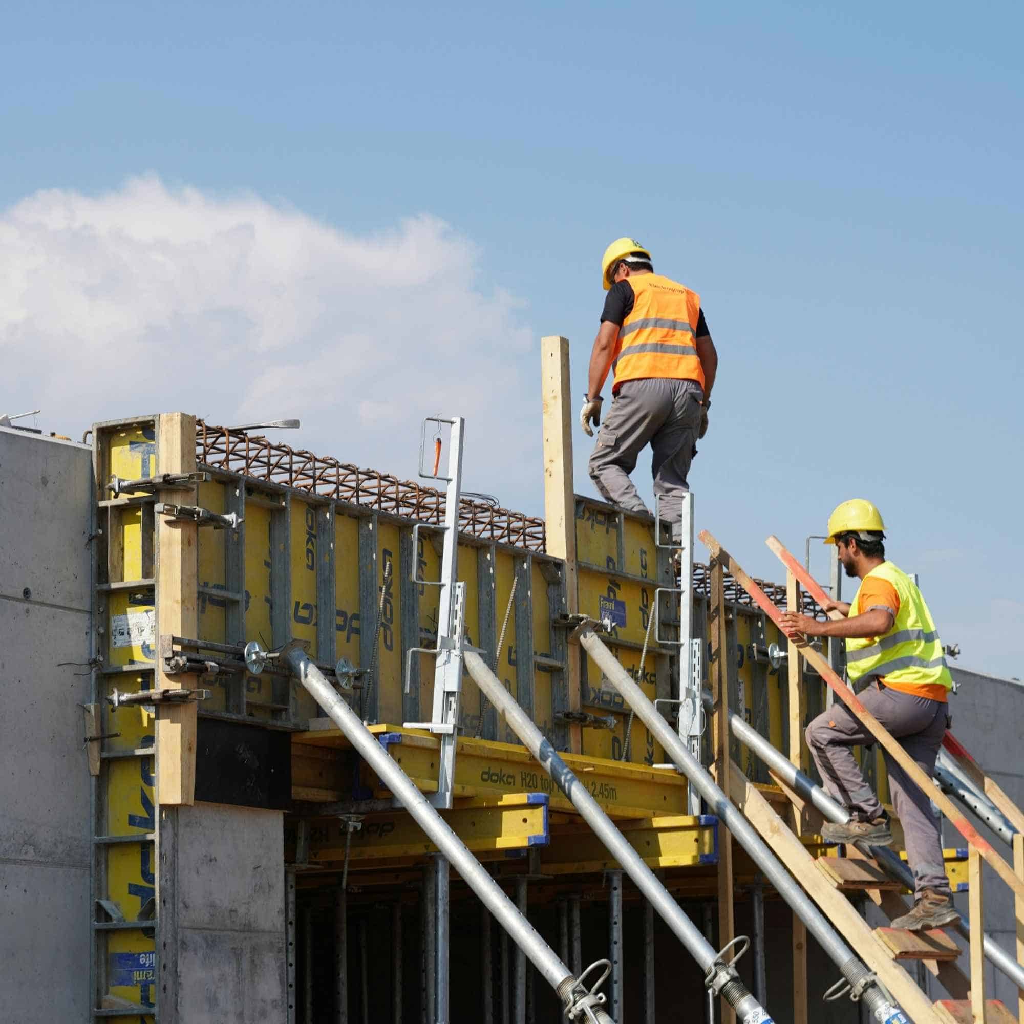 Workers wearing safety helmets and high-visibility vests are actively engaged in construction activities.