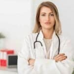 The Ultimate Guide to Professional Practice Structures: Optimizing for Tax, Protection, and Growth A confident female doctor with a stethoscope around her neck, standing in a bright medical office, ready to provide healthcare services.