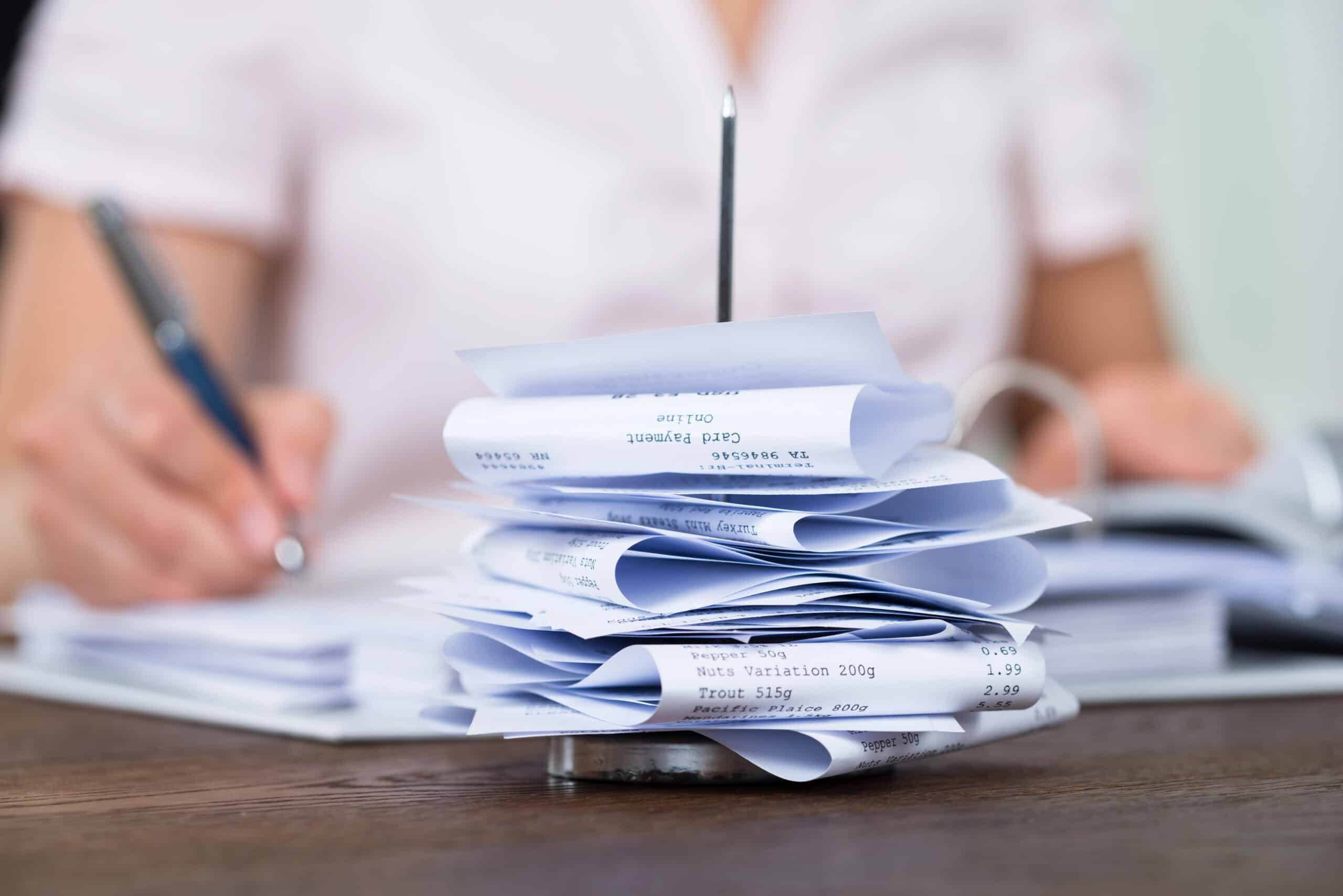 Person managing a large stack of tax papers and documents, highlighting the need for professional accounting and tax advisory services in Beverly Hills, NSW.