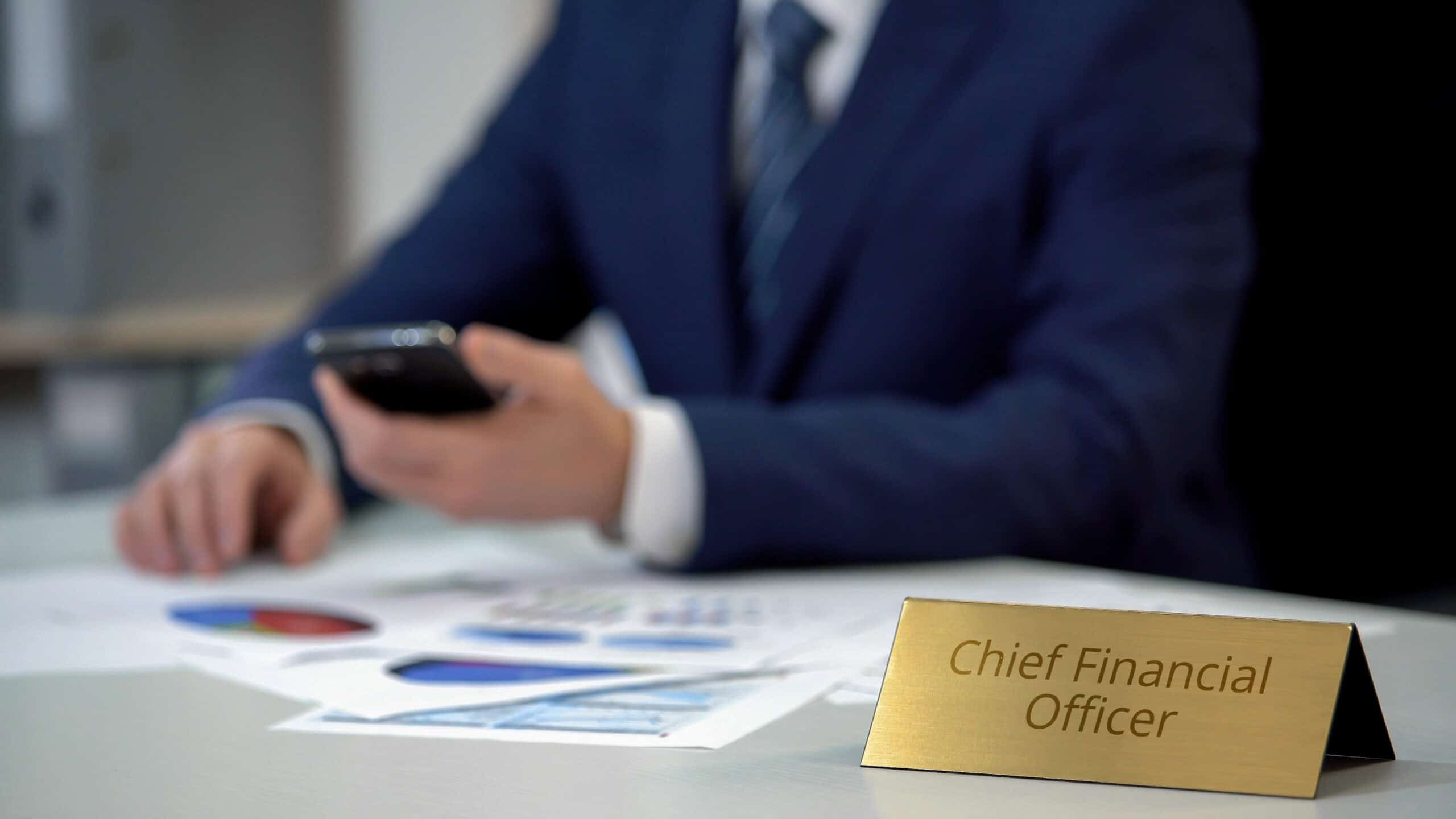 A professional businessman in a suit holding a smartphone during a financial planning meeting.
