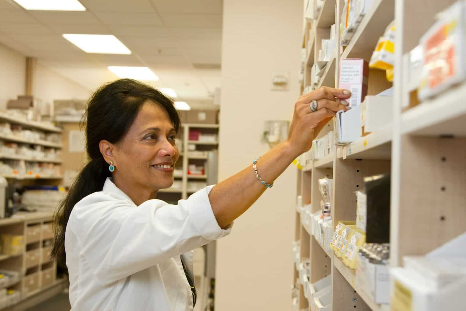 Pharmacist selecting medication on pharmacy shelves, representing accountants for pharmacies in Sydney
