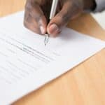 Person signing loan contract documents at a desk, representing a Division 7A loan