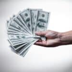 Hand offering a fan of cash, representing gift tax rules in Australia