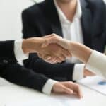 Two people shaking hands across a desk, representing due diligence when buying a business in Australia